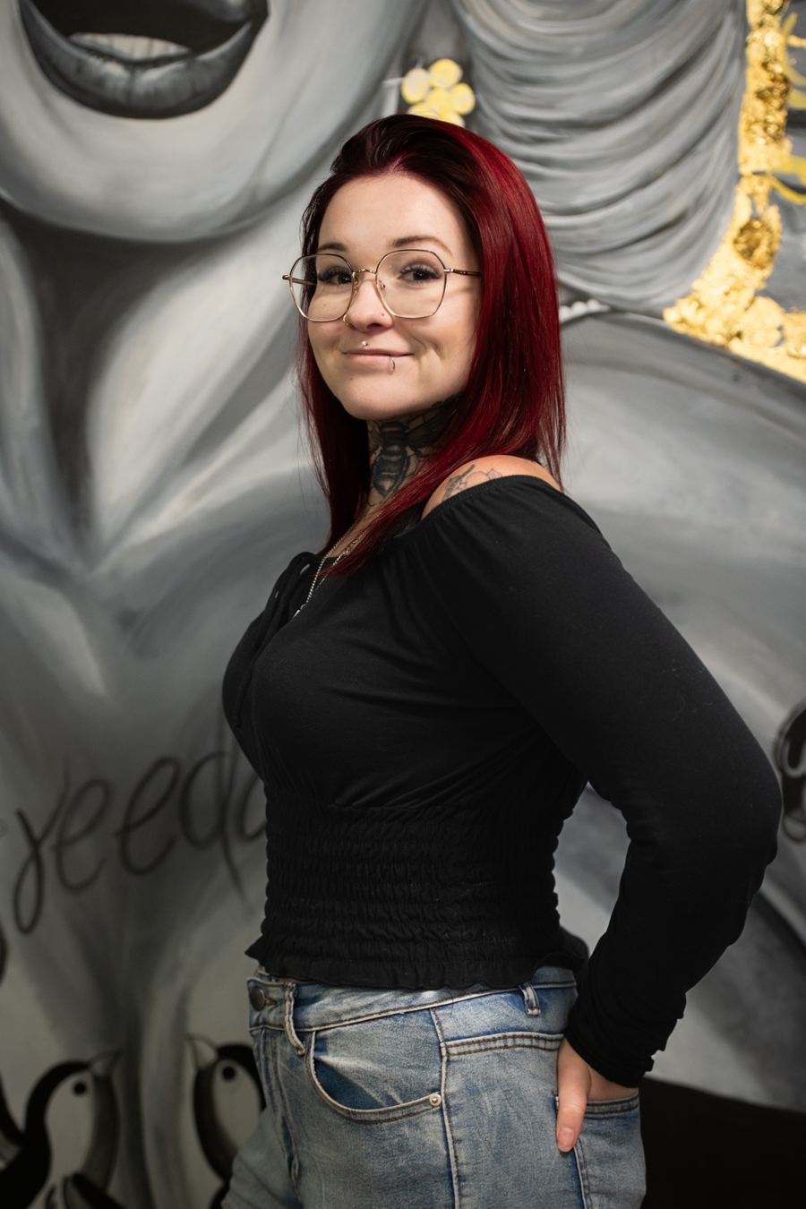 Artiste de Nana Tattoo devant la murale du studio — présentation à venir