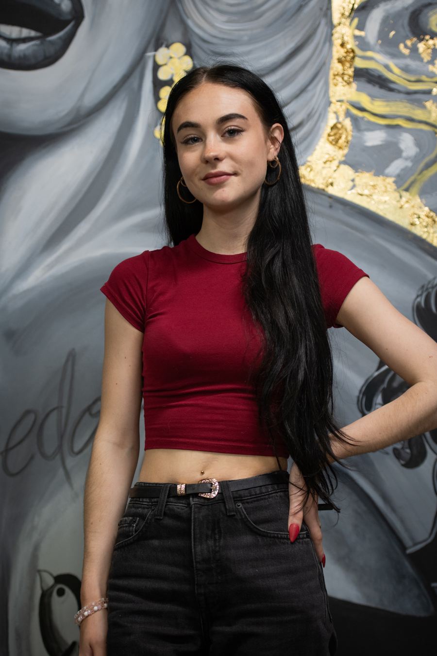 Artiste de Nana Tattoo devant la murale du studio — présentation à venir