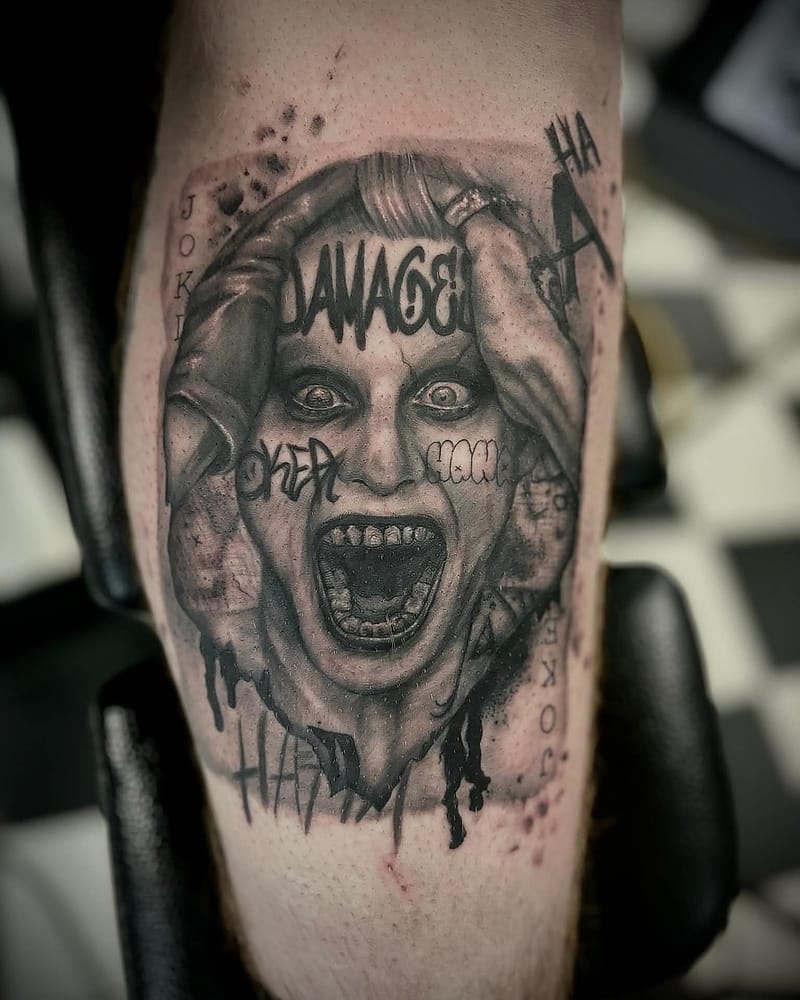Portrait du Joker hurlant sur une carte à jouer, réalisme black and grey sur le mollet