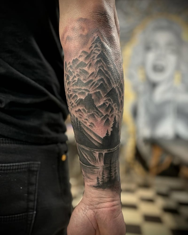Paysage de montagnes, sapins et lac avec chute, black and grey sur l'avant-bras