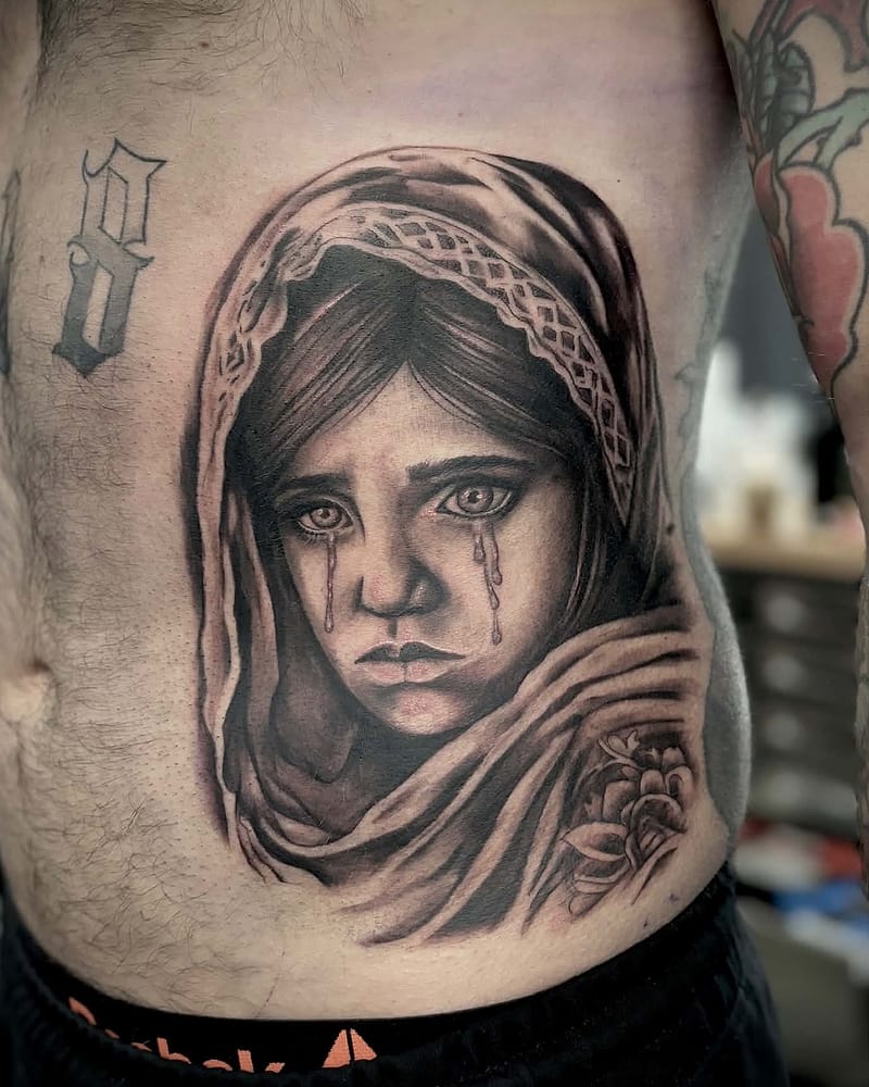 Portrait réaliste d'une fillette au voile, larmes aux yeux, avec une rose, black and grey sur le flanc