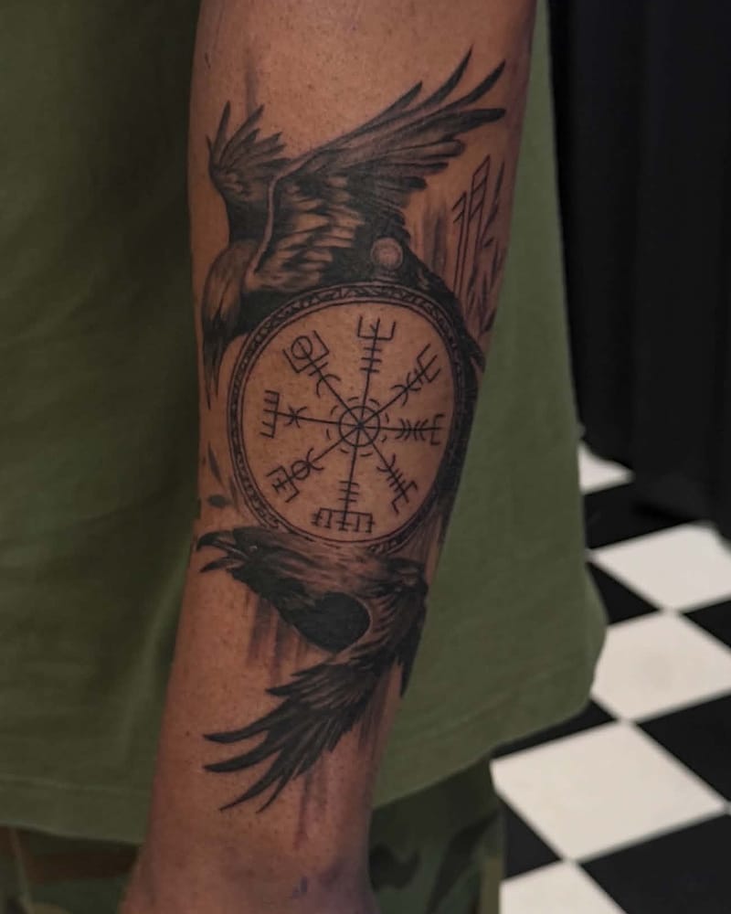 Deux corbeaux encadrant une boussole viking vegvísir, sur l'avant-bras